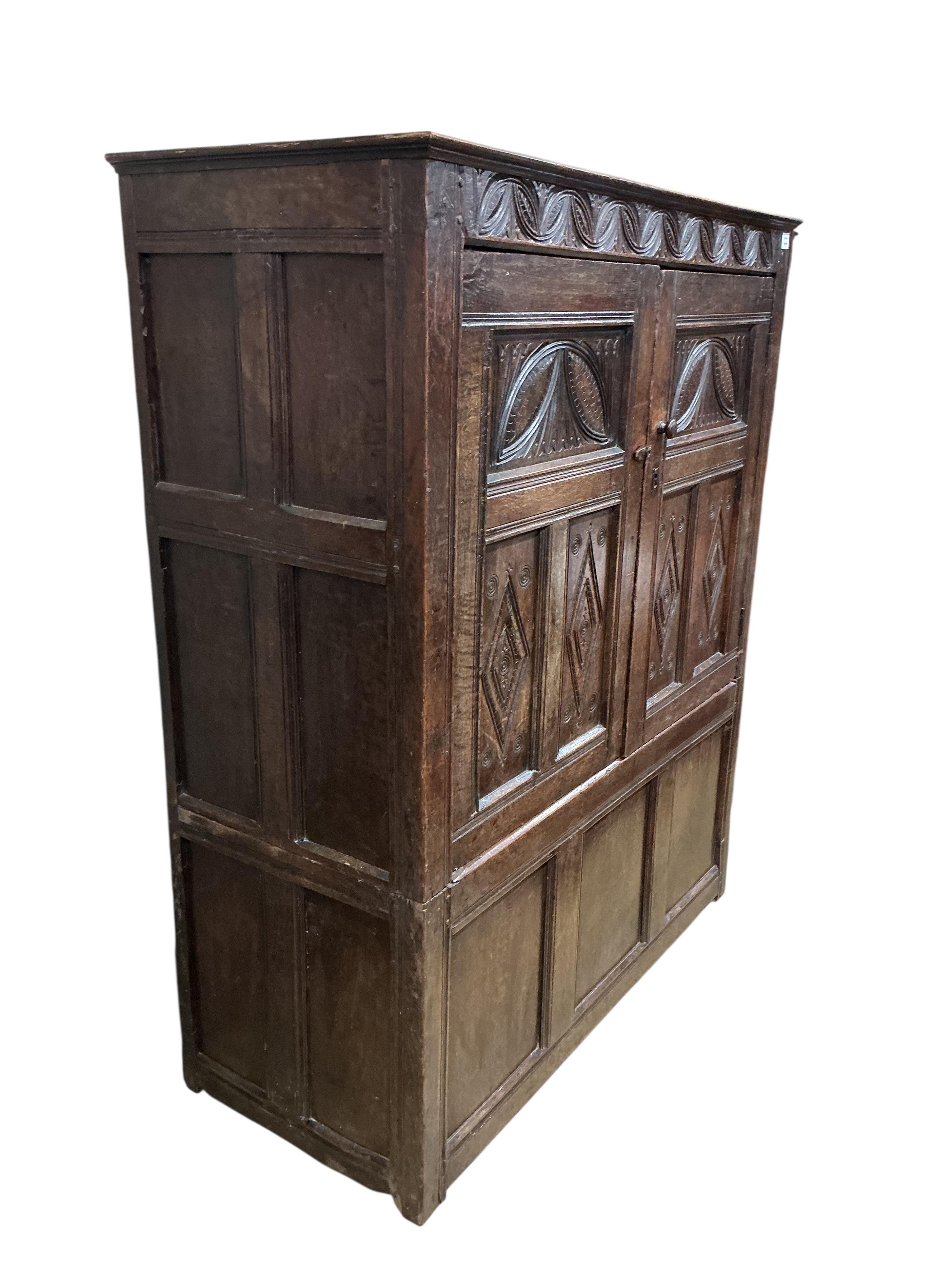 An early 18th century carved oak hanging cupboard, width 133cm, depth 56cm, height 162cm